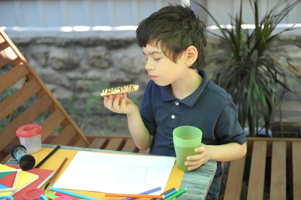 子供の男の子はお菓子でお茶を飲むために休憩を取ります 自宅で夏休み屋外 — ストック写真