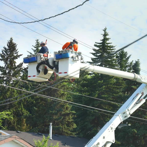 İki elektrikçi bir kamyon vincindeki elektrik kablolarını kontrol ediyor.