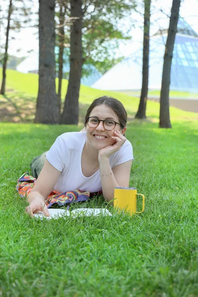 Mutlu Öğrenci Kadın Çim Üzerinde Bir Kitapla Parkta Dinleniyor — Stok fotoğraf