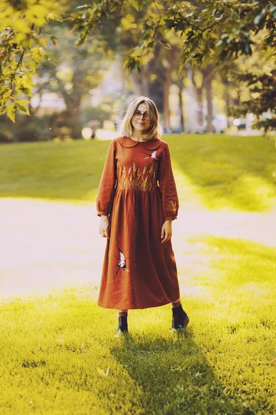 美丽的年轻女子穿着棕色长裙在秋天的公园里散步 很惬意 — 图库照片