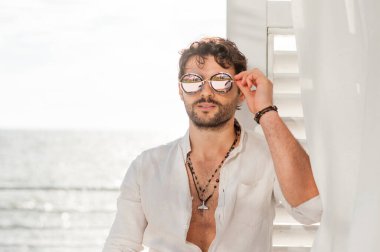 Beyaz gömlekli yakışıklı manken portresi, deniz manzaralı.