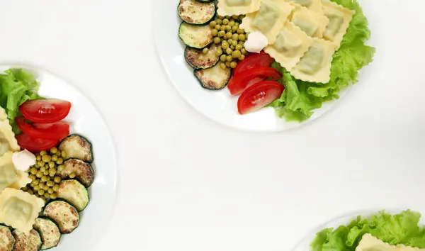 White background with vegan plates with delicious ravioli and vegetables