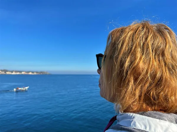 Woman looking at the sea and volcano Etna in Sicily, Acitrezza