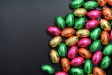 Folyo, çok renkli paskalya yumurtalarını pembeye, yeşile, turuncuya ve bir yığın içinde sarıya sarmalayıp gri siyah bir zemin oluşturur.. 