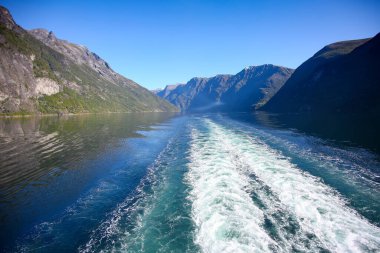 Wake of the cruise ship while scenic cruising down geiranger fjord. Beautiful landscape with reflections of the mountains in the water on a calm summer day, Norwegian fjords, Norway. 