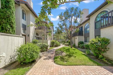 Beton yolu olan apartmanlar ve Carlsbad, San Diego, ABD 'de ağaçları olan bahçeler. 26 Haziran 2025