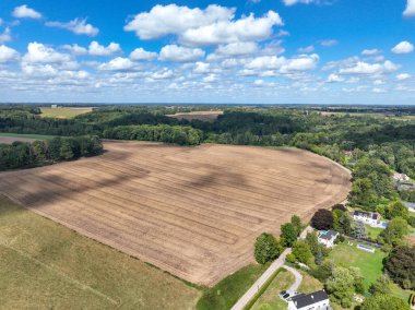 Aerial view of farmland surrounded by forest with blue sky during summer in the Belgian province of Walloon Brabant