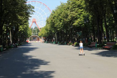 Main alley of Gorky Park in Kharkov with a Ferris wheel at the end on a sunny summers day. 