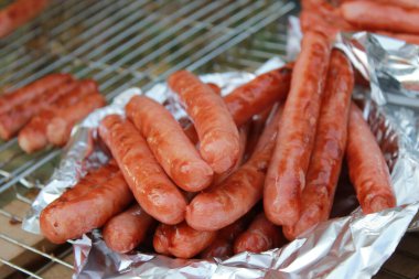 Grilled Sausages. Grilled sausages on aluminum foil clipart