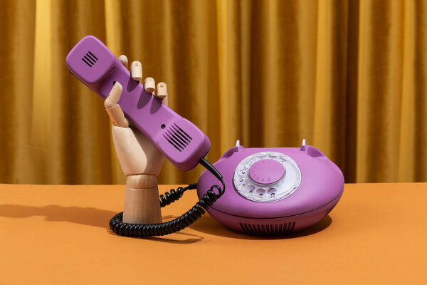 Wooden hand dials a number on a retro phone. Conceptual photo. High quality photo