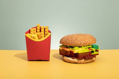 Renkli arkaplanda lego tuğlalardan yapılmış hamburger ve patates kızartması plastik konsept fotoğraf, abur cubur. Yüksek kalite fotoğraf