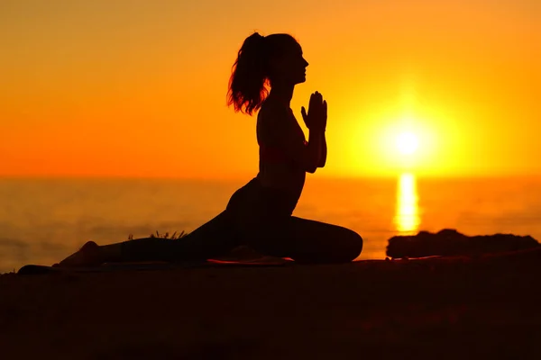 一名女子在日落时在海滩上做瑜伽的侧视图画像 — 图库照片