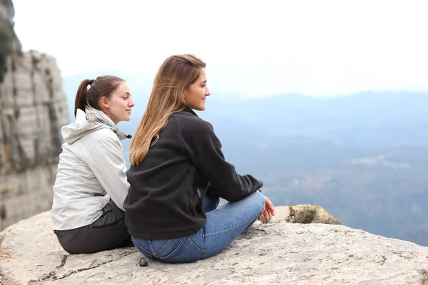 两个徒步旅行者坐在悬崖边观景 — 图库照片