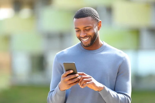 Mutlu Siyah Adam Sokakta Yürürken Cep Telefonunu Kontrol Ediyor — Stok fotoğraf