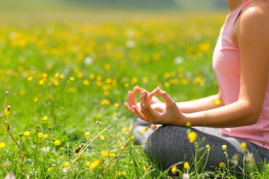 Doğada yeşil bir alanda yoga yapan bir kadının yakın çekimi.