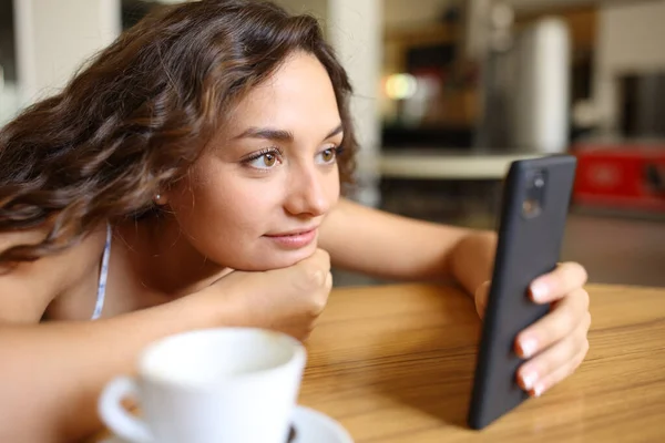 Kobieta Sprawdzająca Zawartość Smartfona Siedząca Kawiarni — Zdjęcie stockowe