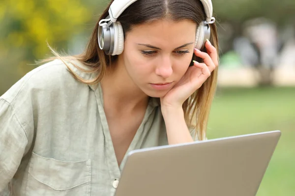 Nastolatek Słuchawkami Sprawdza Laptopa Siedzącego Parku — Zdjęcie stockowe