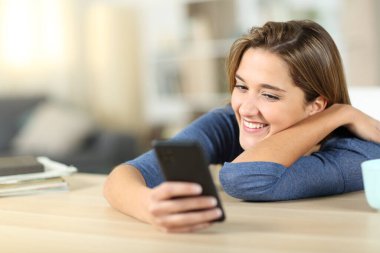 Mutlu kadın evde akıllı telefon içeriğini kontrol ediyor