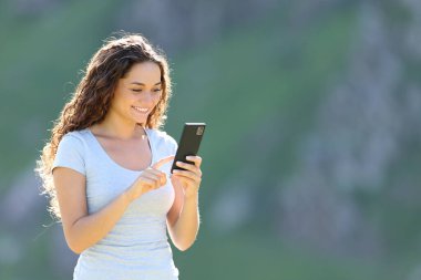 Cep telefonuyla dağda dikilen mutlu kadın.