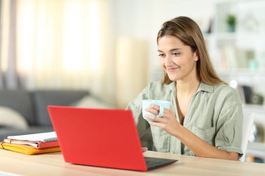 Öğrenci evde laptopla kahve içiyor.