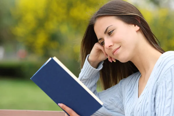 Teen reading a paper book in a park