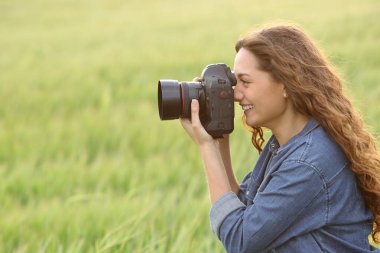 Side view portrait of a woman taking photos in a field