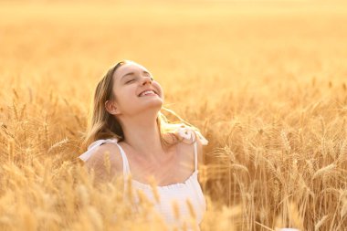Happy woman breathing fresh air in a golden field