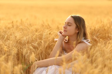 Woman relaxing alone in a field at sunset