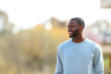Happy black man walking looking at side in a park