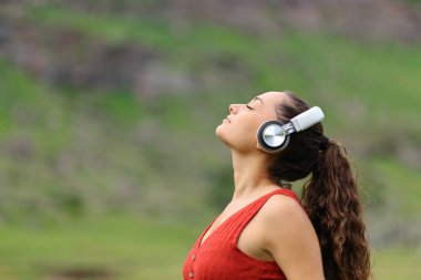 Side view portrait of a woman meditating listening audio guide in nature