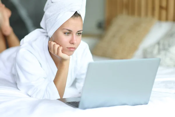 在床上洗澡后使用笔记本电脑的妇女 — 图库照片