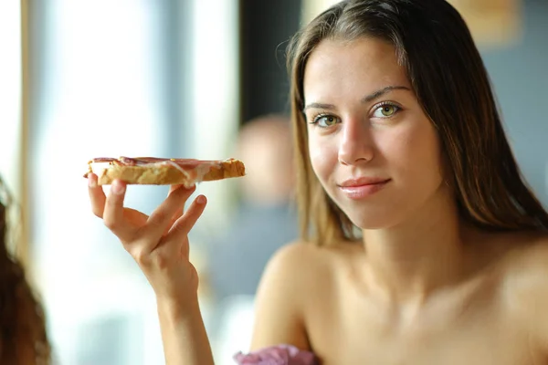 女人看着相机 手里拿着面包和果酱 — 图库照片
