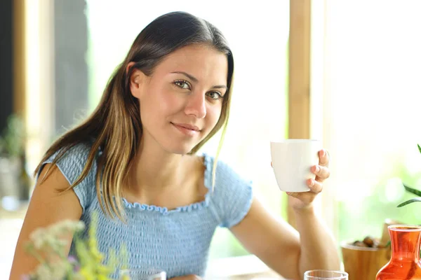 满意的女人拿着咖啡杯在餐馆摆出一副相机的样子 — 图库照片