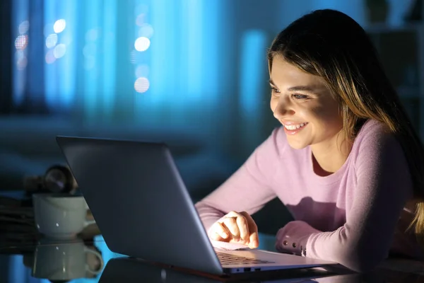 幸せな女性は夜に自宅でノートパソコンでメディアを見て — ストック写真