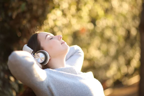 Розслаблена Жінка Навушниках Відпочиває Слухаючи Аудіо Сидячи Лавці Заході Сонця — стокове фото