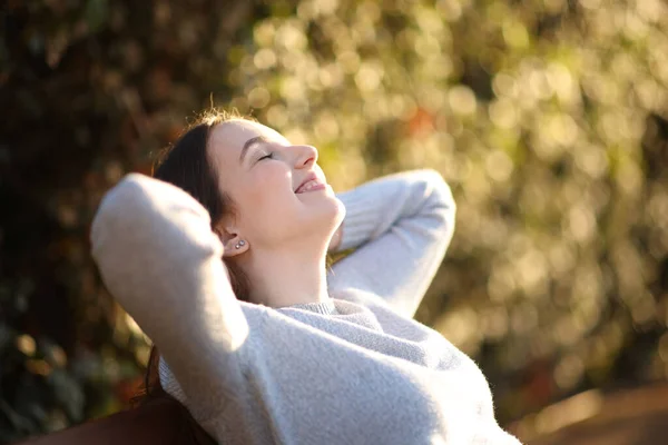 日落时 快乐的女人坐在长椅上笑着 — 图库照片