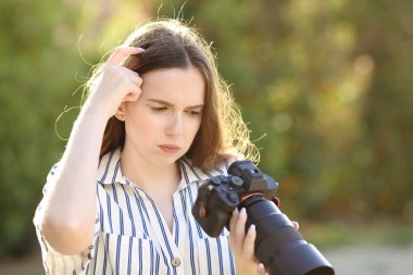 Üzgün fotoğrafçı parktaki aynasız kamerada fotoğraflara bakıyor.