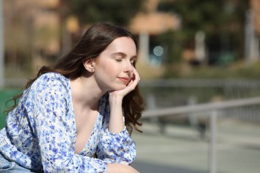 Rahat bir kadın güneşli bir günde parkta dinleniyor.