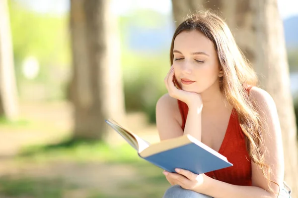 深刻な女性読書A紙本で座っている公園晴れた日 — ストック写真