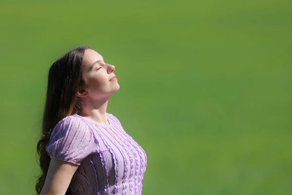 大自然中一个在绿色背景下呼吸新鲜空气的女人的侧视图画像 — 图库照片