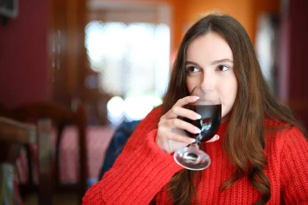 Woman in red sweater drinking soda sitting in a bar