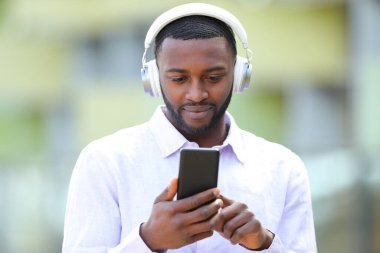 Sokaklarda müzik dinleyen siyah bir adamın ön manzara portresi.