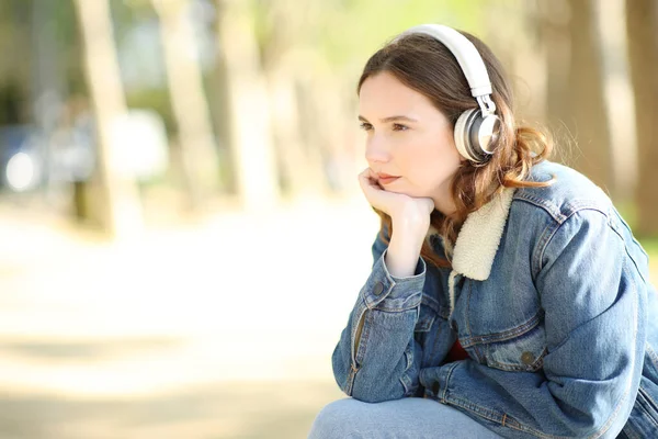 Mulher Ouvindo Áudio Com Telefone Auditivo Contemplando Sentar Parque — Fotografia de Stock