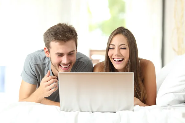 フロントビューポートレートの面白いカップル笑って見てノートパソコンのコンテンツ上のベッド — ストック写真
