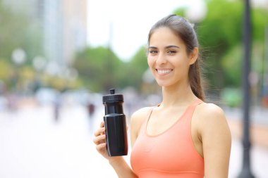 Elinde su şişesi olan mutlu koşucu sokakta sana bakıyor.