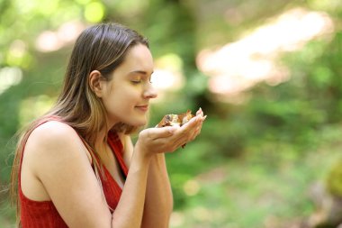 Happy woman smelling death leafs in a forest clipart