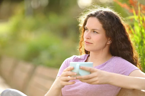 公園でコーヒーを飲みながらベンチに座っている女 — ストック写真