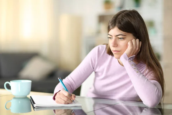 Distraído Adolescente Escrevendo Notebook Olhando Para Longe Casa — Fotografia de Stock