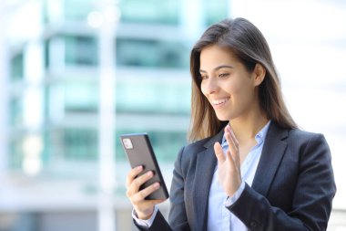 Sokaktaki bir telefon görüşmesinde mutlu yönetici el sallıyor.