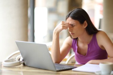 Öğrenci, bar terasında bir lapeop ile göz yorgunluğu çekiyor.